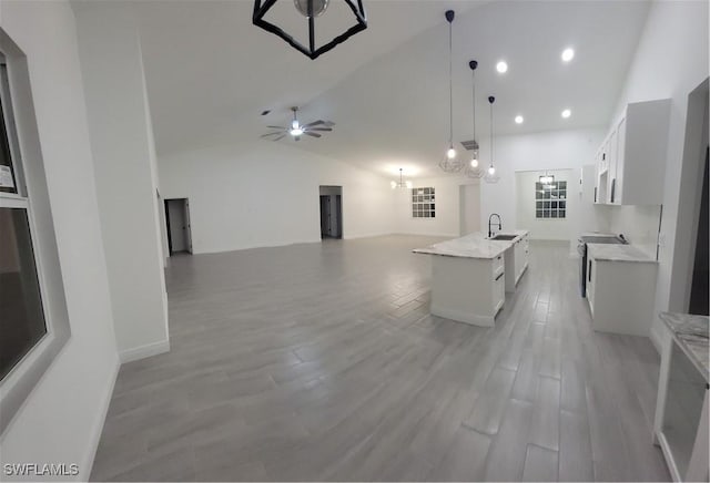 kitchen featuring a center island with sink, pendant lighting, white cabinets, and open floor plan