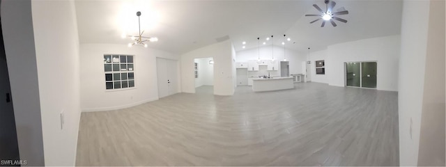 unfurnished living room with high vaulted ceiling, ceiling fan with notable chandelier, and light hardwood / wood-style floors