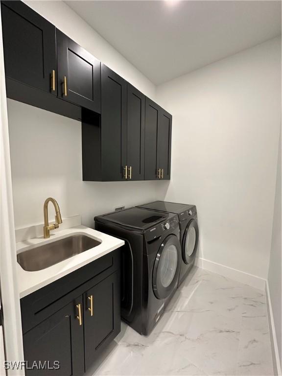 washroom featuring washing machine and clothes dryer, sink, and cabinets