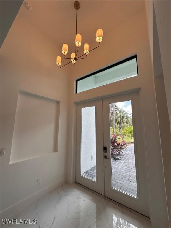 doorway to outside with french doors, a towering ceiling, and a chandelier