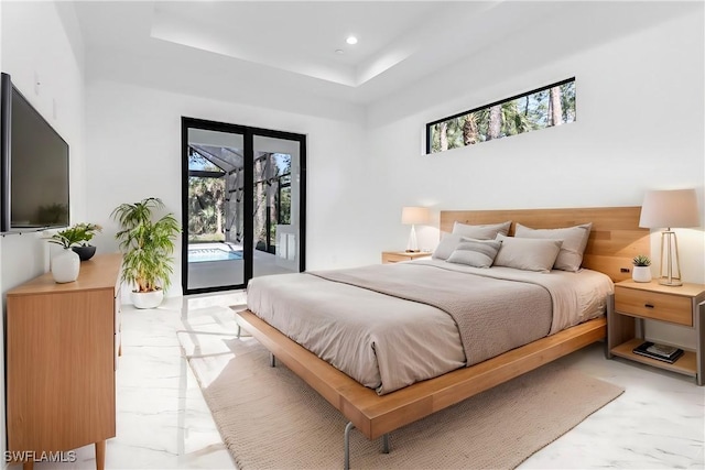 bedroom with access to outside and a raised ceiling