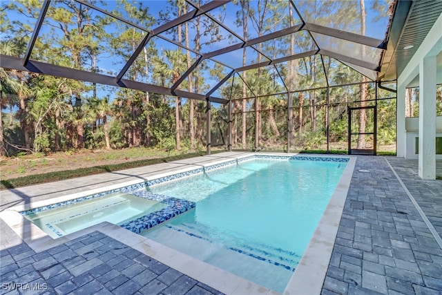 view of swimming pool featuring glass enclosure, a patio area, and an in ground hot tub