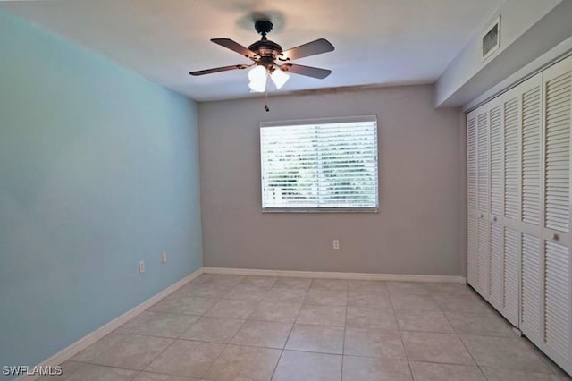 unfurnished bedroom with ceiling fan, a closet, and light tile patterned floors