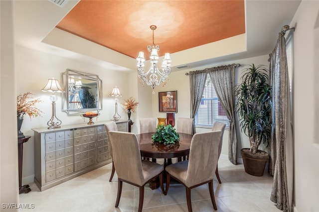 dining area with a raised ceiling and a notable chandelier