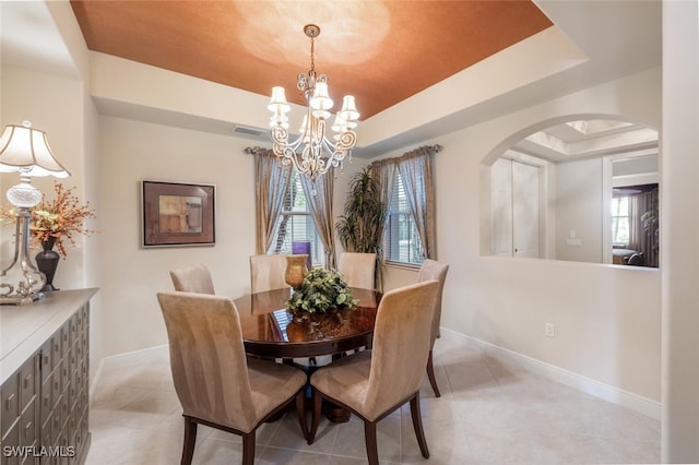 tiled dining room with a raised ceiling and an inviting chandelier