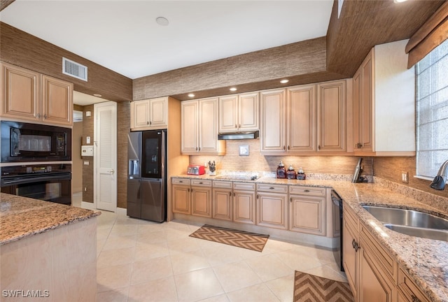 kitchen with sink, light stone counters, light brown cabinetry, light tile patterned floors, and black appliances