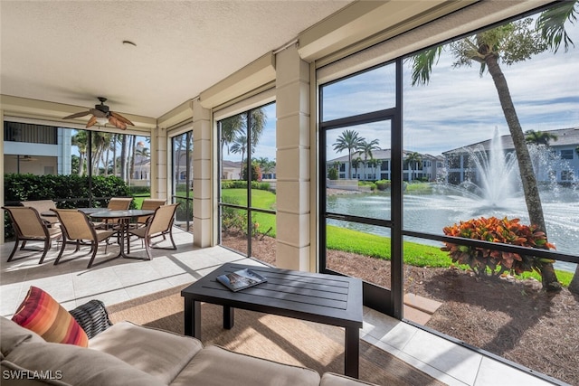 sunroom featuring a water view and ceiling fan