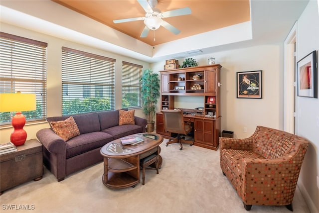 carpeted living room featuring a raised ceiling and ceiling fan