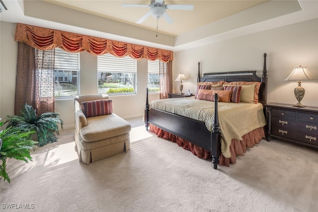 bedroom with carpet flooring, ceiling fan, and a raised ceiling