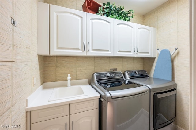 clothes washing area with washer and dryer, cabinets, and sink