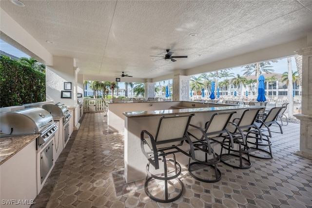 view of patio / terrace with area for grilling, a grill, exterior bar, and ceiling fan