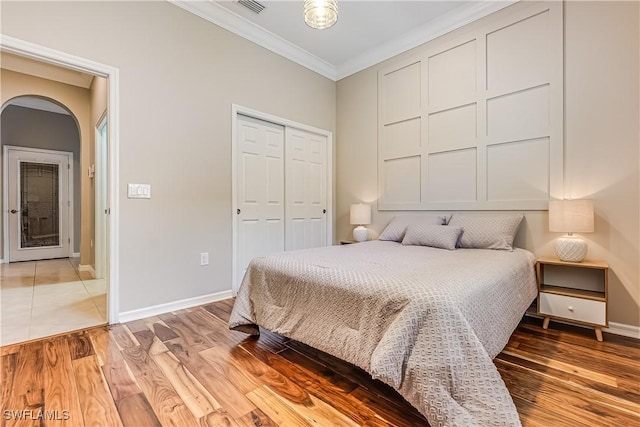 bedroom featuring light hardwood / wood-style floors, ornamental molding, and a closet