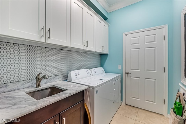 washroom featuring sink, cabinets, separate washer and dryer, light tile patterned flooring, and ornamental molding