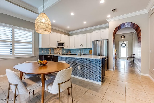 kitchen with white cabinets, appliances with stainless steel finishes, a kitchen island with sink, and sink