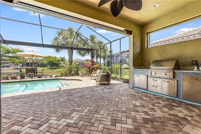 view of pool with a grill, ceiling fan, a patio area, and exterior kitchen