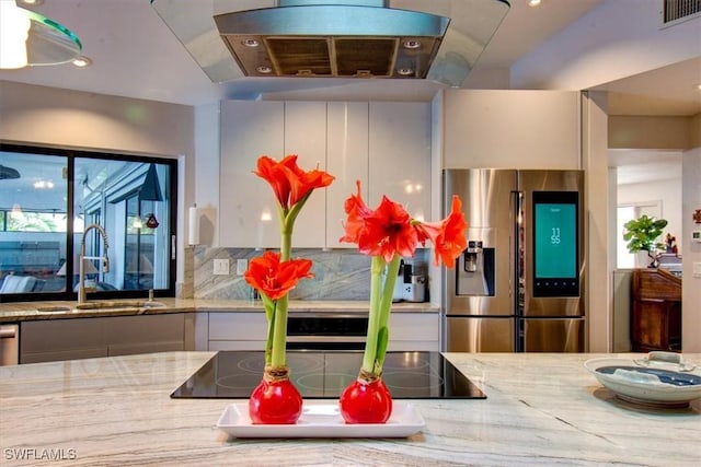 kitchen featuring white cabinets, stainless steel fridge with ice dispenser, light stone counters, and sink