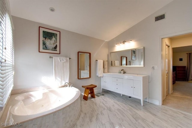 bathroom with tiled bath, vanity, and lofted ceiling