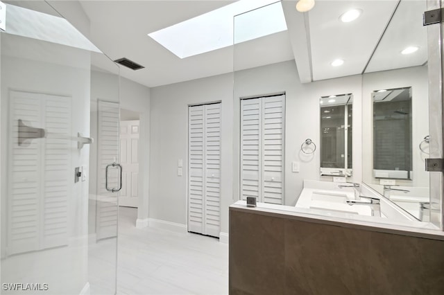 bathroom with vanity, a skylight, and a shower with door