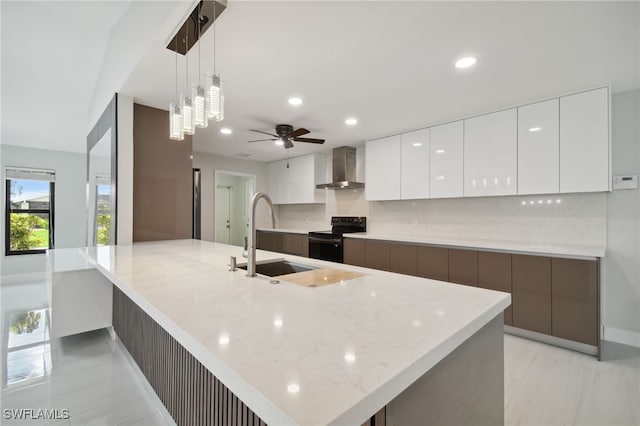 kitchen featuring wall chimney exhaust hood, sink, pendant lighting, white cabinetry, and black electric range oven