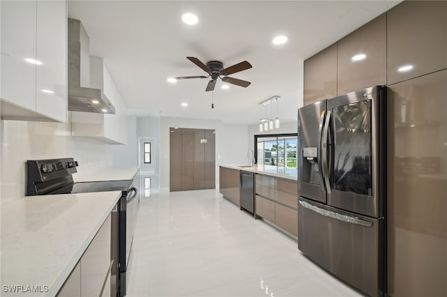 kitchen with appliances with stainless steel finishes, light stone counters, ceiling fan, wall chimney range hood, and decorative light fixtures