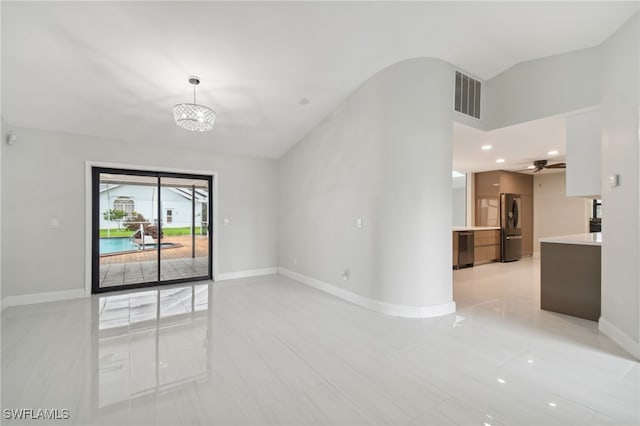 empty room with ceiling fan with notable chandelier and vaulted ceiling