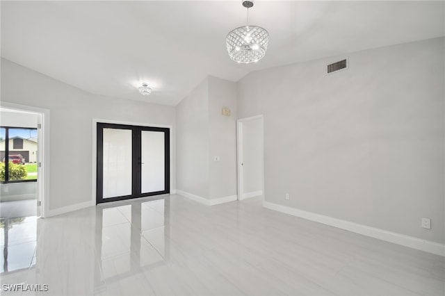 unfurnished room with a notable chandelier, lofted ceiling, and french doors