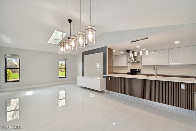 kitchen with vaulted ceiling with skylight, wall chimney range hood, decorative light fixtures, white cabinets, and black range with electric stovetop