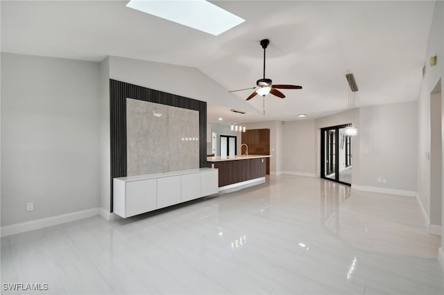 unfurnished living room with ceiling fan, sink, and lofted ceiling with skylight