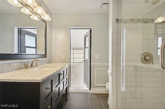 bathroom with vanity, toilet, and tiled shower