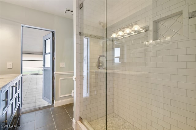 bathroom with tile patterned flooring, vanity, toilet, and a shower with shower door