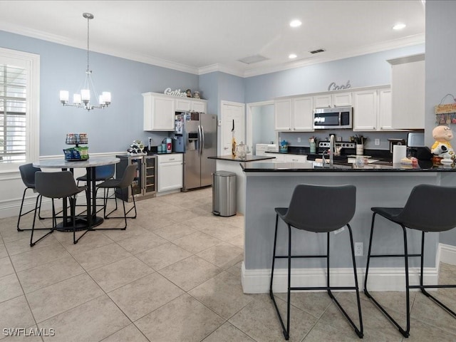 kitchen featuring ornamental molding, appliances with stainless steel finishes, kitchen peninsula, and white cabinets