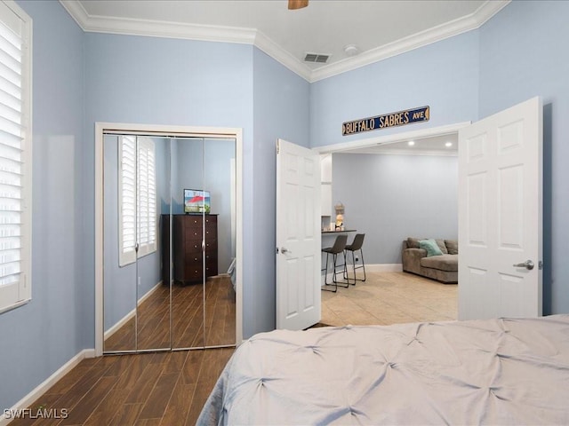 bedroom with multiple windows, crown molding, ceiling fan, and a closet