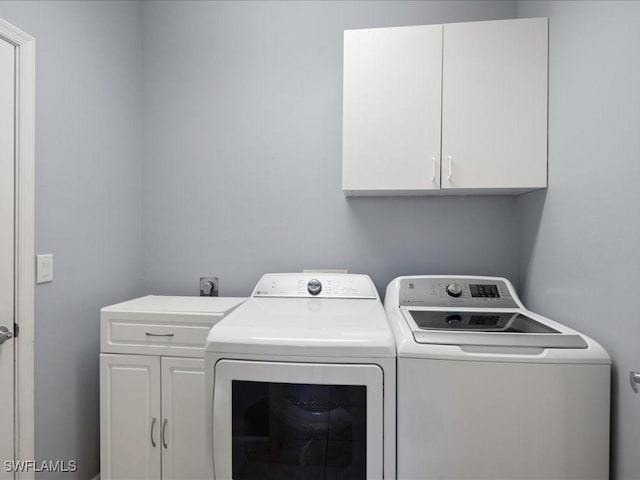 laundry area featuring cabinets, separate washer and dryer, and sink