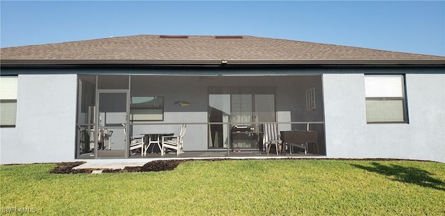 rear view of property with a sunroom, a patio area, and a lawn