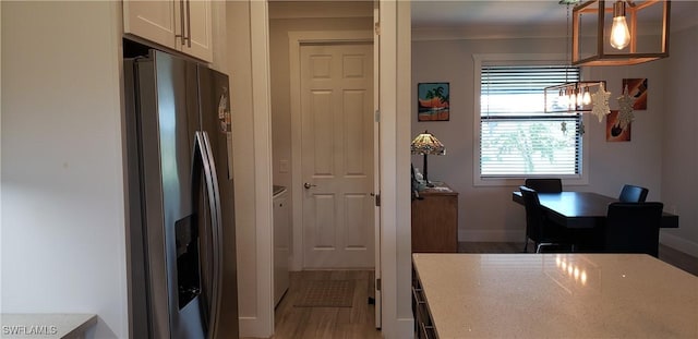 kitchen featuring light stone countertops, hardwood / wood-style floors, decorative light fixtures, white cabinets, and stainless steel fridge with ice dispenser