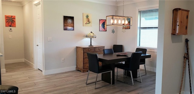 dining room with crown molding, plenty of natural light, light hardwood / wood-style floors, and an inviting chandelier