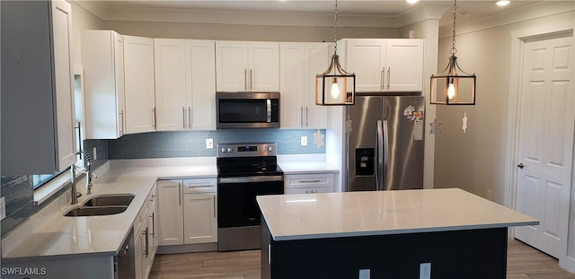 kitchen with white cabinets, hanging light fixtures, sink, appliances with stainless steel finishes, and a kitchen island