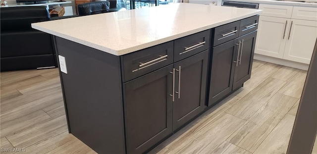 kitchen with white cabinetry, a kitchen island, and light wood-type flooring