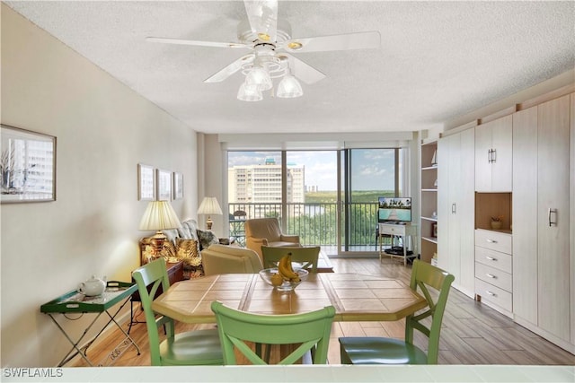 dining area with ceiling fan, light wood-type flooring, and a textured ceiling