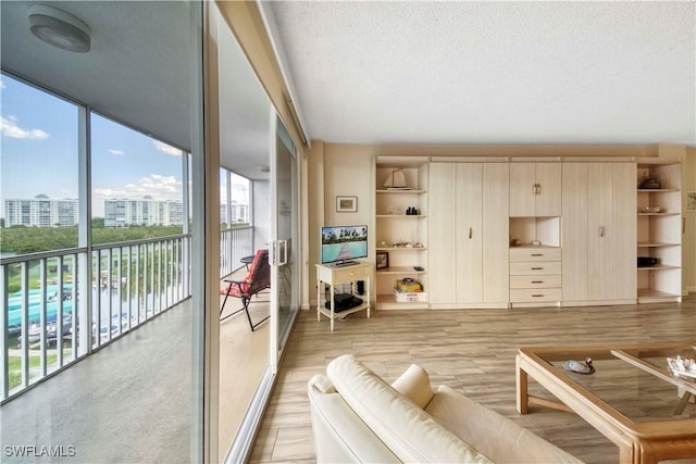 living room with a wealth of natural light, a textured ceiling, and a wall of windows