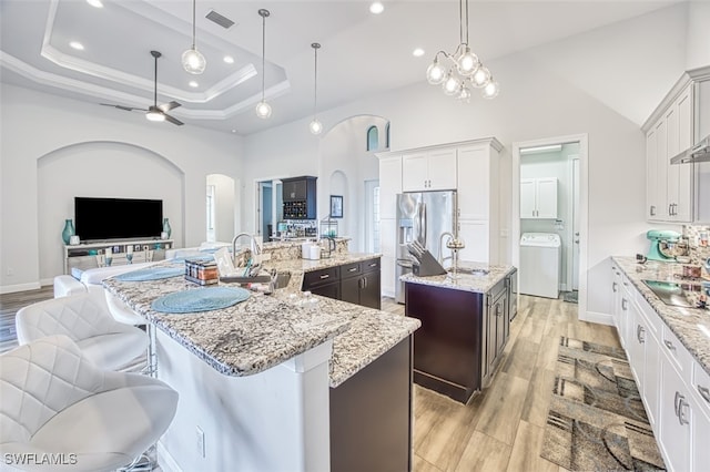 kitchen with ceiling fan, sink, pendant lighting, a spacious island, and washer / dryer