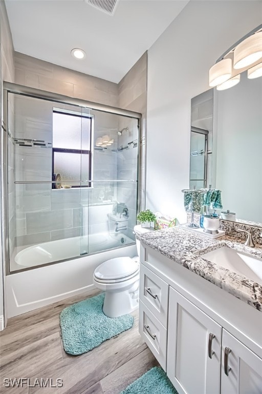 full bathroom featuring vanity, shower / bath combination with glass door, toilet, and wood-type flooring