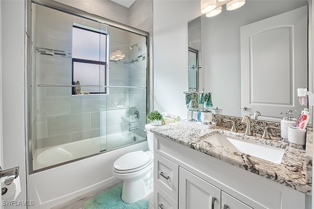 full bathroom featuring vanity, bath / shower combo with glass door, and toilet