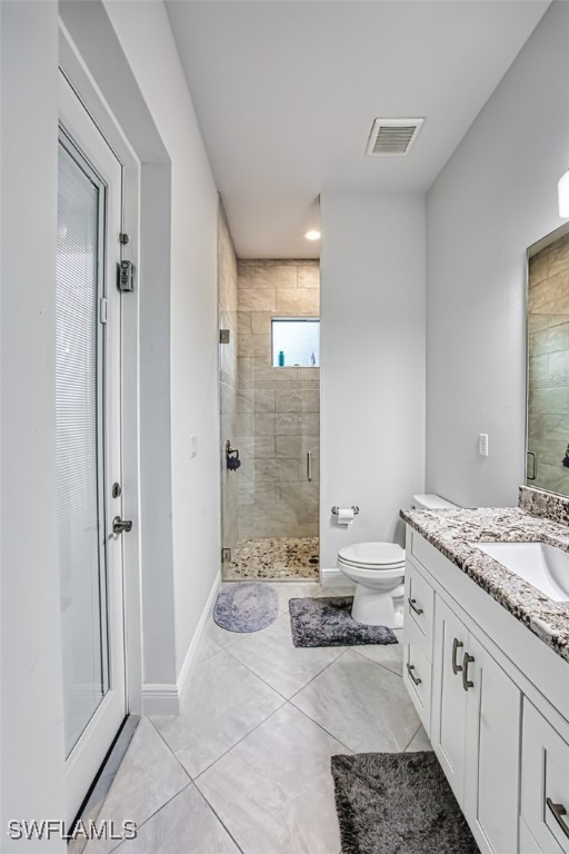 bathroom featuring tile patterned flooring, vanity, an enclosed shower, and toilet