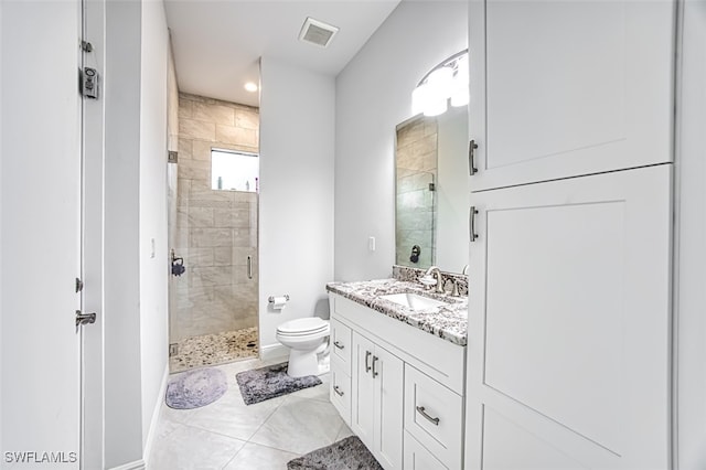 bathroom featuring tile patterned flooring, vanity, toilet, and a shower with shower door