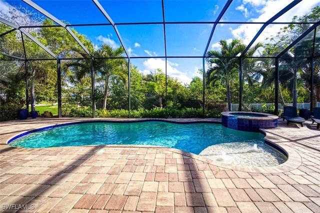 view of pool with glass enclosure, a patio area, and an in ground hot tub