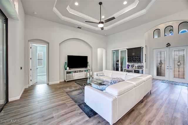 living room with hardwood / wood-style floors, ceiling fan, a tray ceiling, and french doors