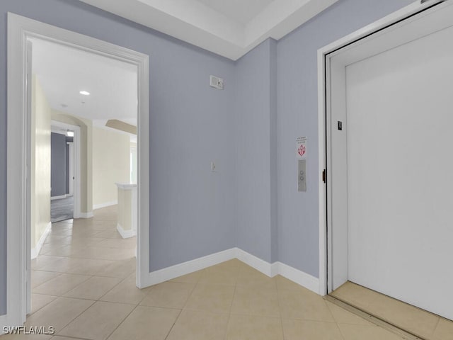 hall featuring light tile patterned floors and elevator