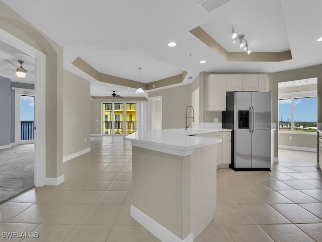 kitchen featuring kitchen peninsula, stainless steel refrigerator with ice dispenser, a raised ceiling, sink, and white cabinets