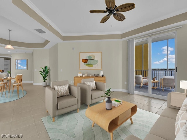 living room with ceiling fan, a raised ceiling, light tile patterned floors, and crown molding